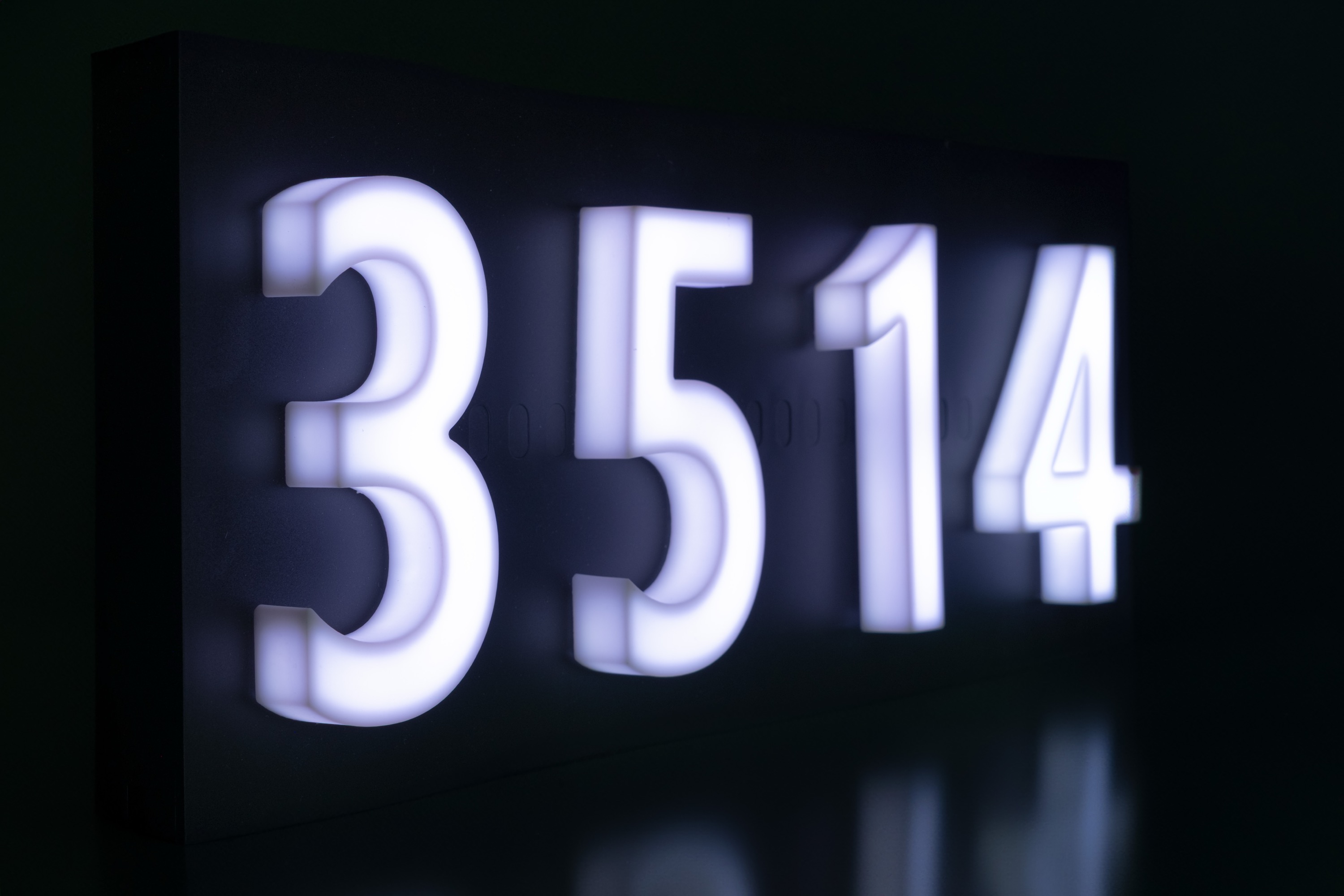 Close-up of illuminated Glomensio Firefly address numbers glowing at night